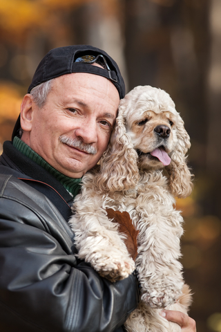 Man holding happy Cocker Spaniel dog outdoors