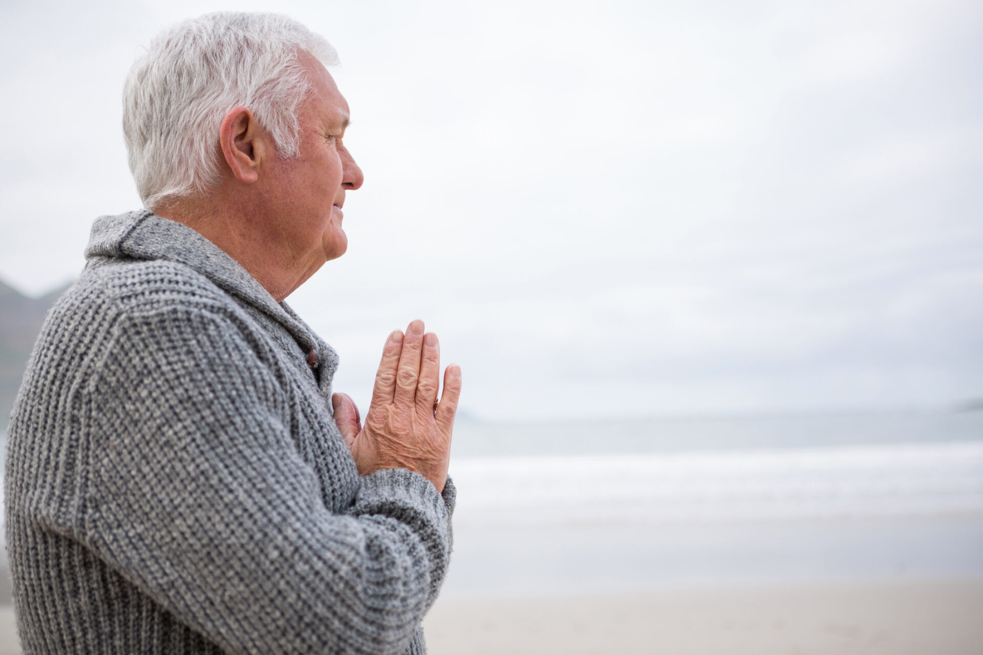 Elderly man meditating on beach