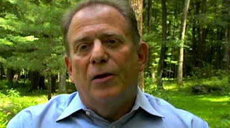 Man in blue shirt outdoors with trees
