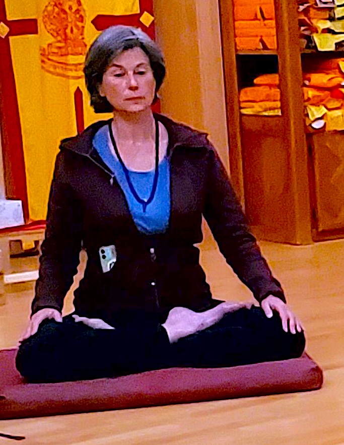 Person meditating cross-legged on red cushion