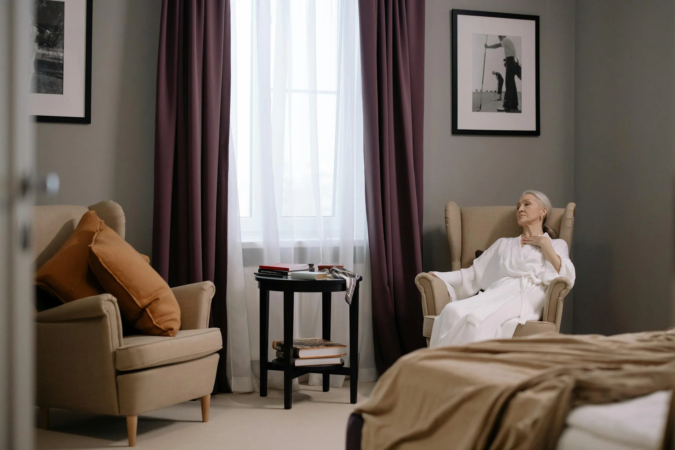 An elderly woman sitting in a living room, practicing nasal breathing, demonstrating a calm and peaceful demeanor.