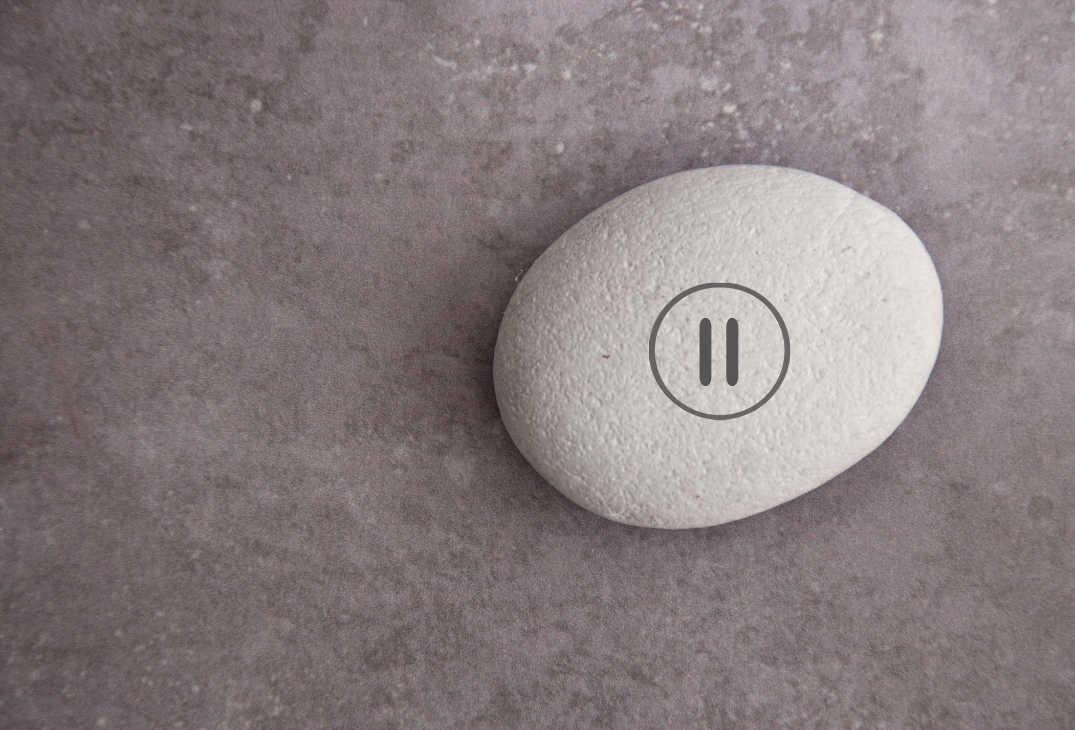 Smooth white pebble with pause symbol