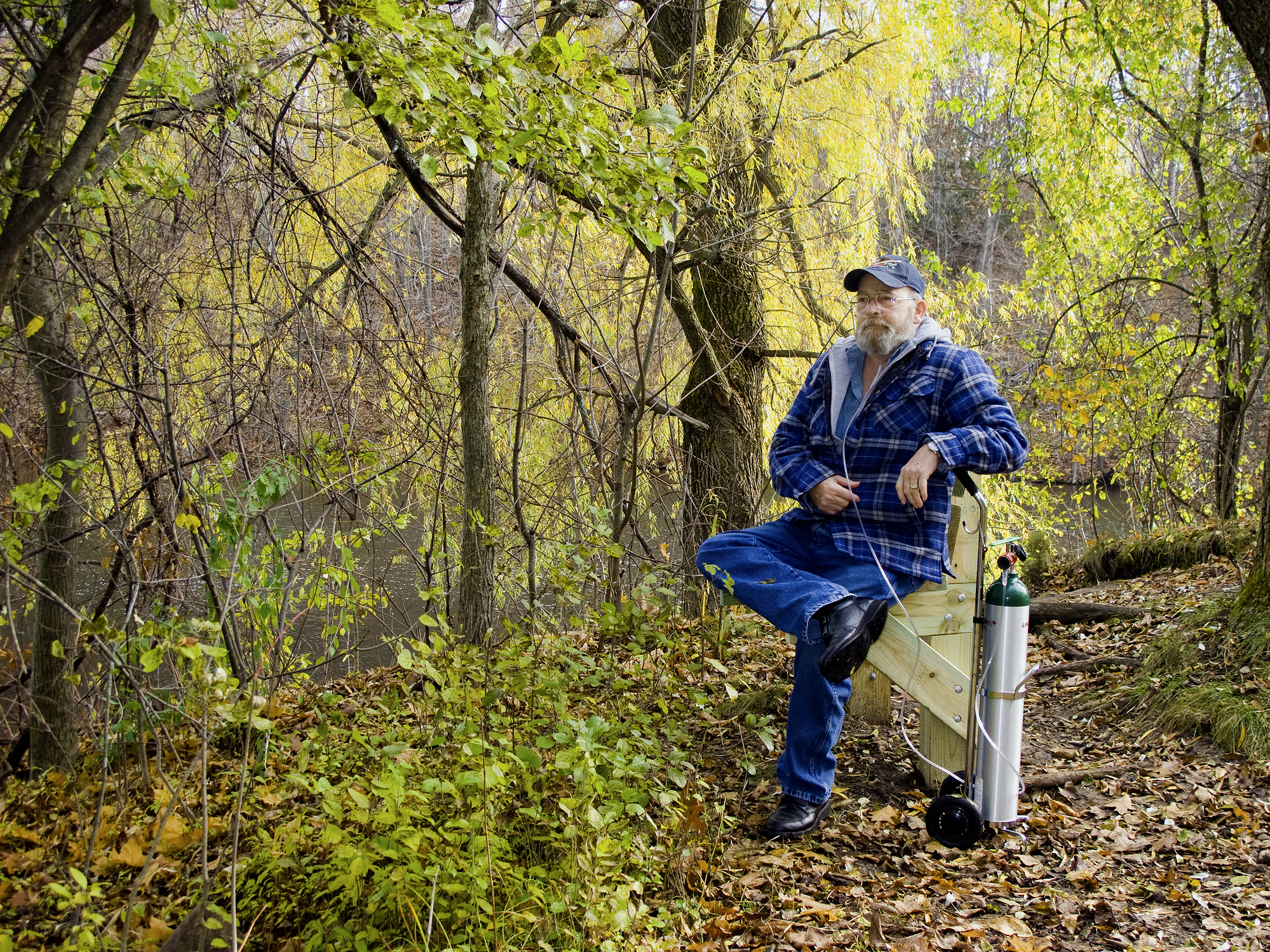 Man with portable oxygen tank sitting outdoors