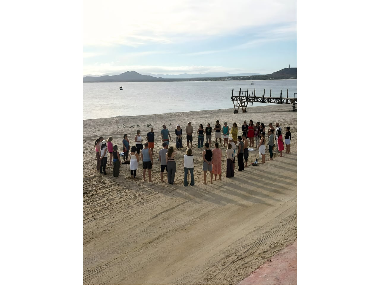 People standing in circle on sandy beach