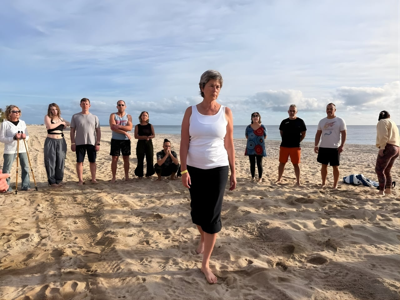 Woman walking barefoot on beach with group